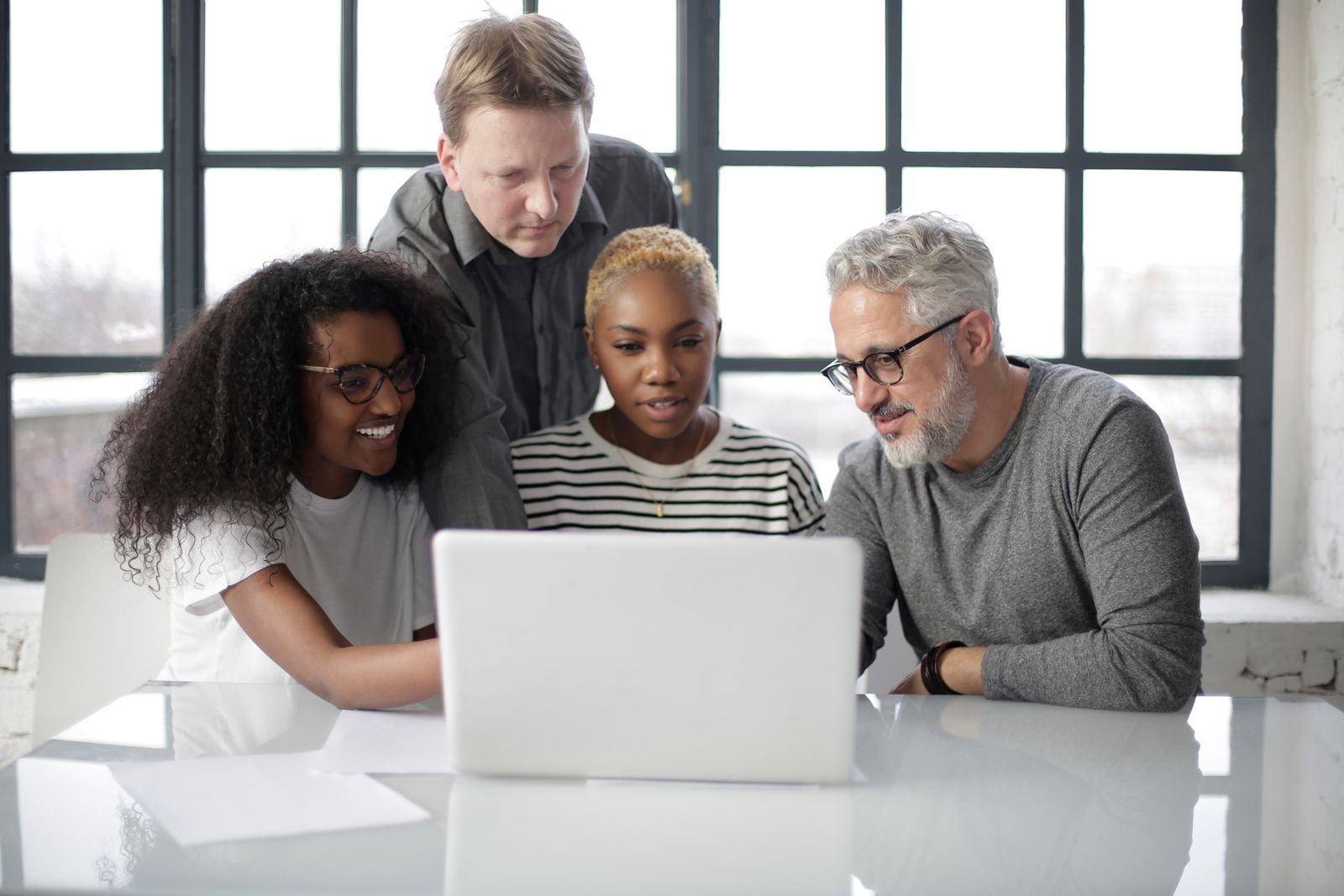 A diverse team collaborating around a laptop in a bright office
